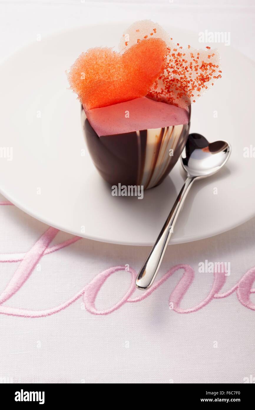 Una pralina rosa decorata con cuori su un tessuto ricamato con la parola "Amore" Foto Stock