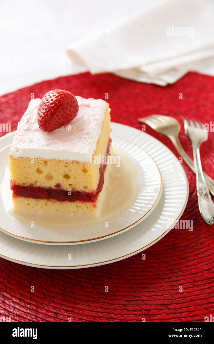 Pezzo di Tres Leches torta con uno strato di fragole; due forcelle Foto Stock