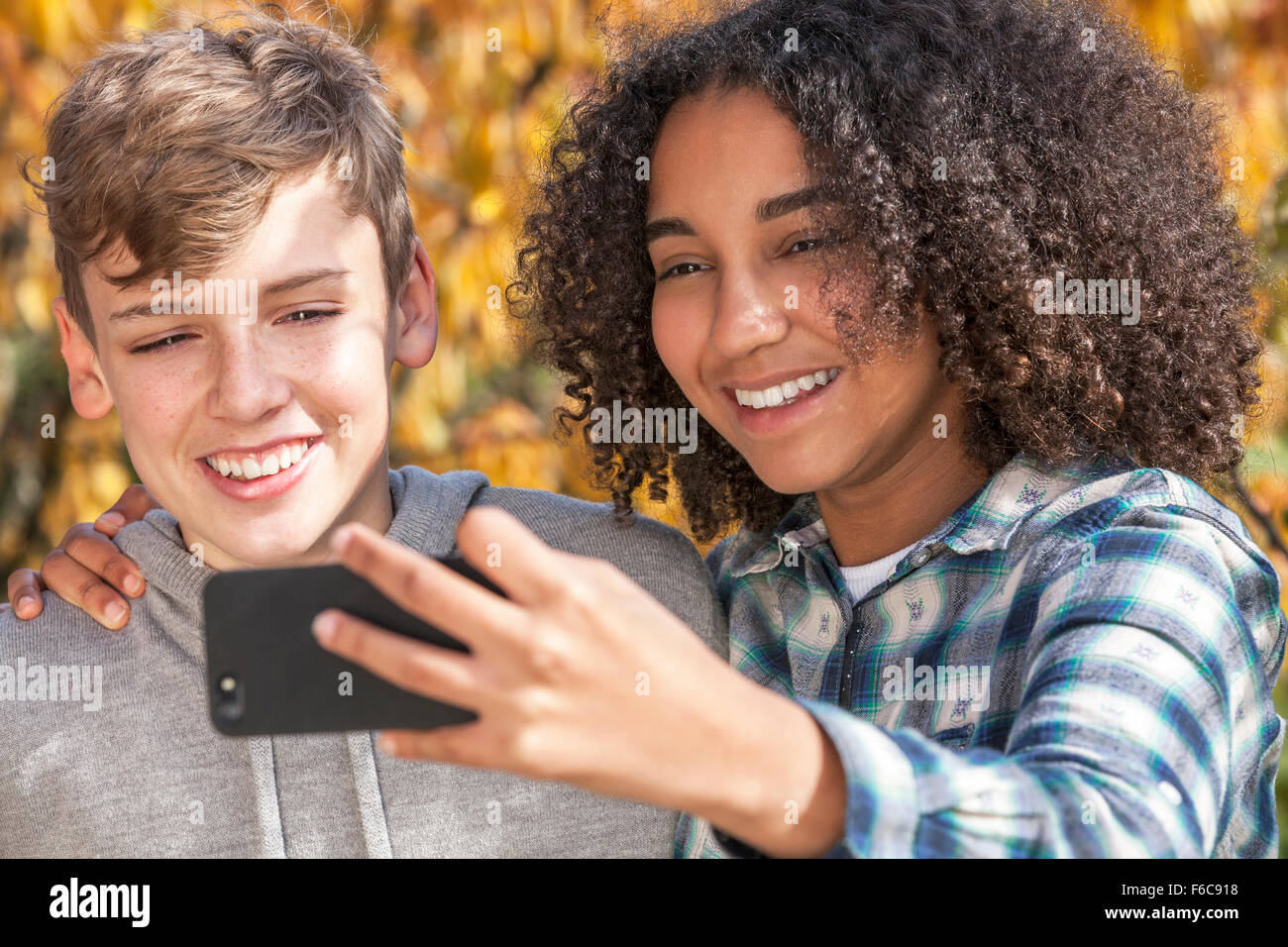 Razza mista gruppo due felici i bambini adolescenti americano africano ragazza ragazzo caucasico ridere insieme prendendo selfie sul telefono cellulare Foto Stock