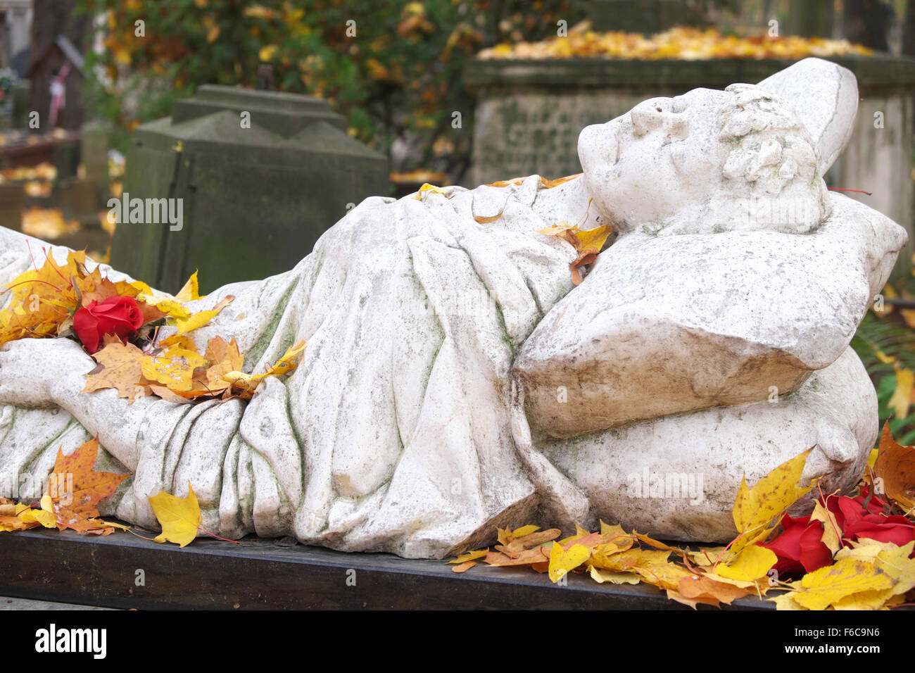 Varsavia POLONIA - Foglie di autunno su una tomba reclinabili figura con rose rosse in grande stile gotico cimitero Powazki Foto Stock