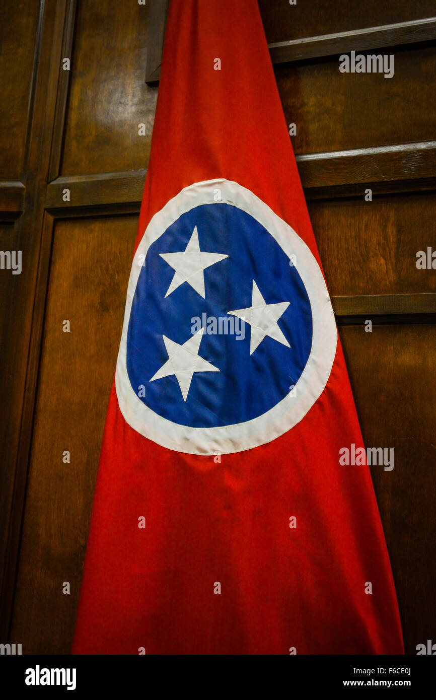 Un colorato di rosso e di blu bandiera con tre stelle bianche in un cerchio che simboleggia il Tennessee State flag prima di un legno parete interna Foto Stock