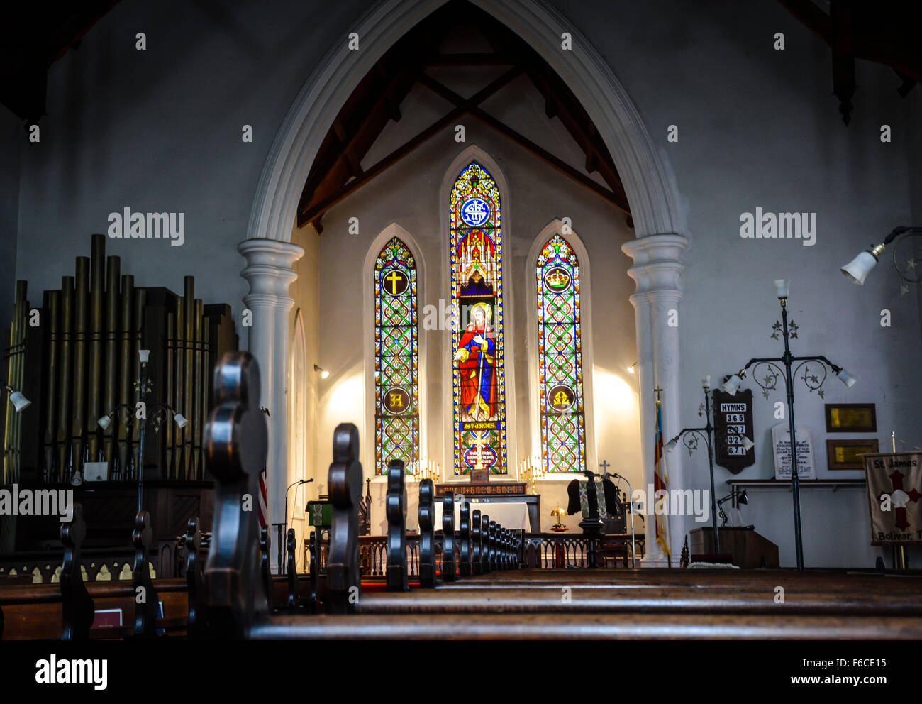 Un sobrio e vuoto interno di una piccola vecchia chiesa protestante con banchi in legno, pulpito decorativo e affascinante il vetro macchiato Foto Stock