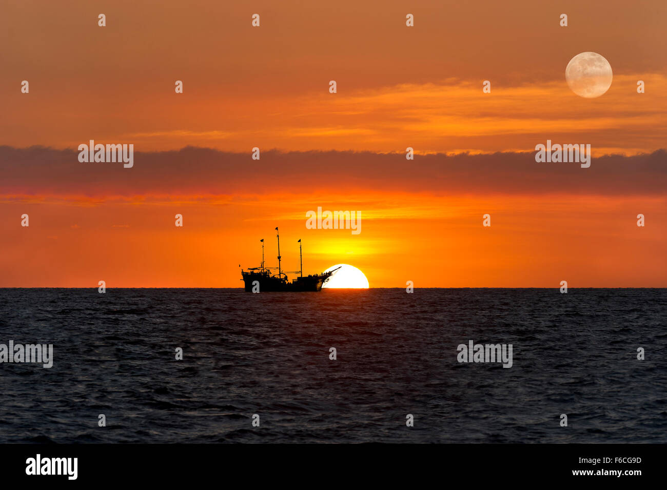 Nave silhouette tramonto è un vecchio legno nave pirata seduti al mare con la luna piena che sorge nel Cielo di tramonto. Foto Stock