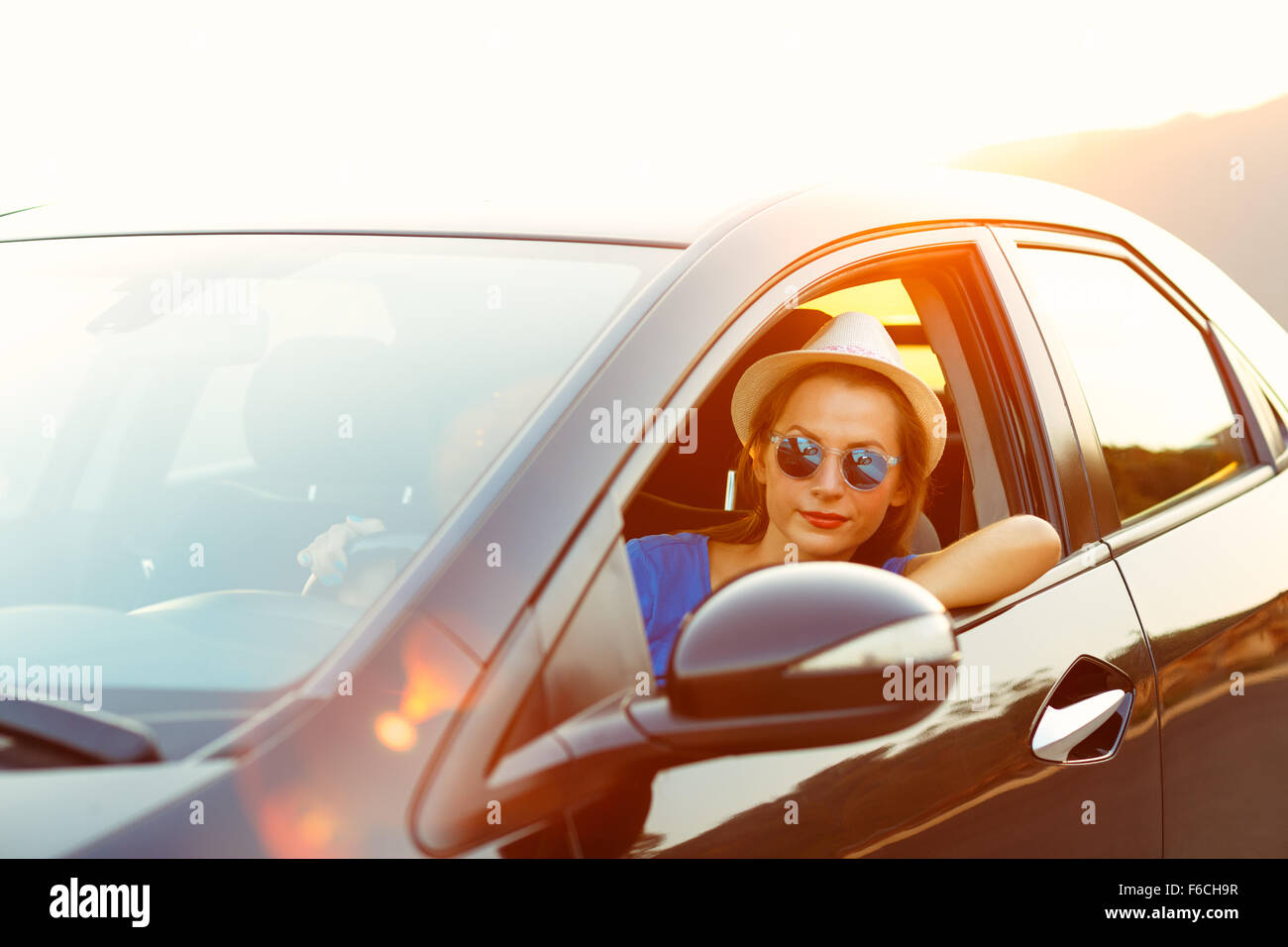 Donna sorridente alla guida di una vettura al tramonto. Concetto di viaggio Foto Stock