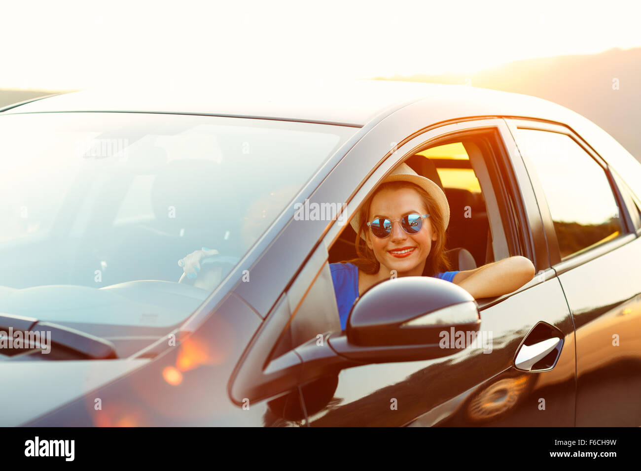 Donna sorridente alla guida di una vettura al tramonto. Concetto di viaggio Foto Stock