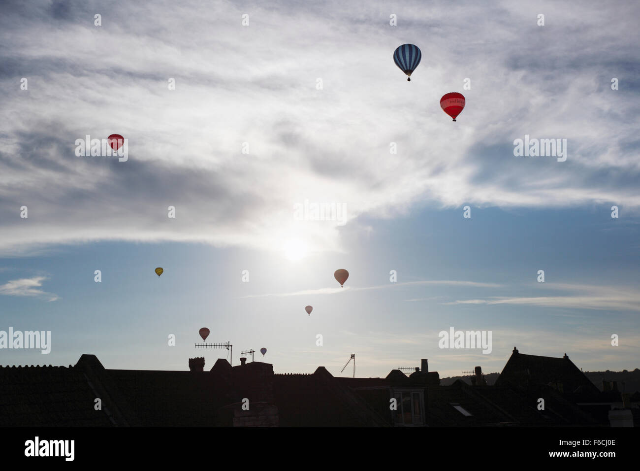 La salita di massa di aria calda Mongolfiere sopra i tetti. Bristol Balloon Fiesta. Regno Unito. Foto Stock
