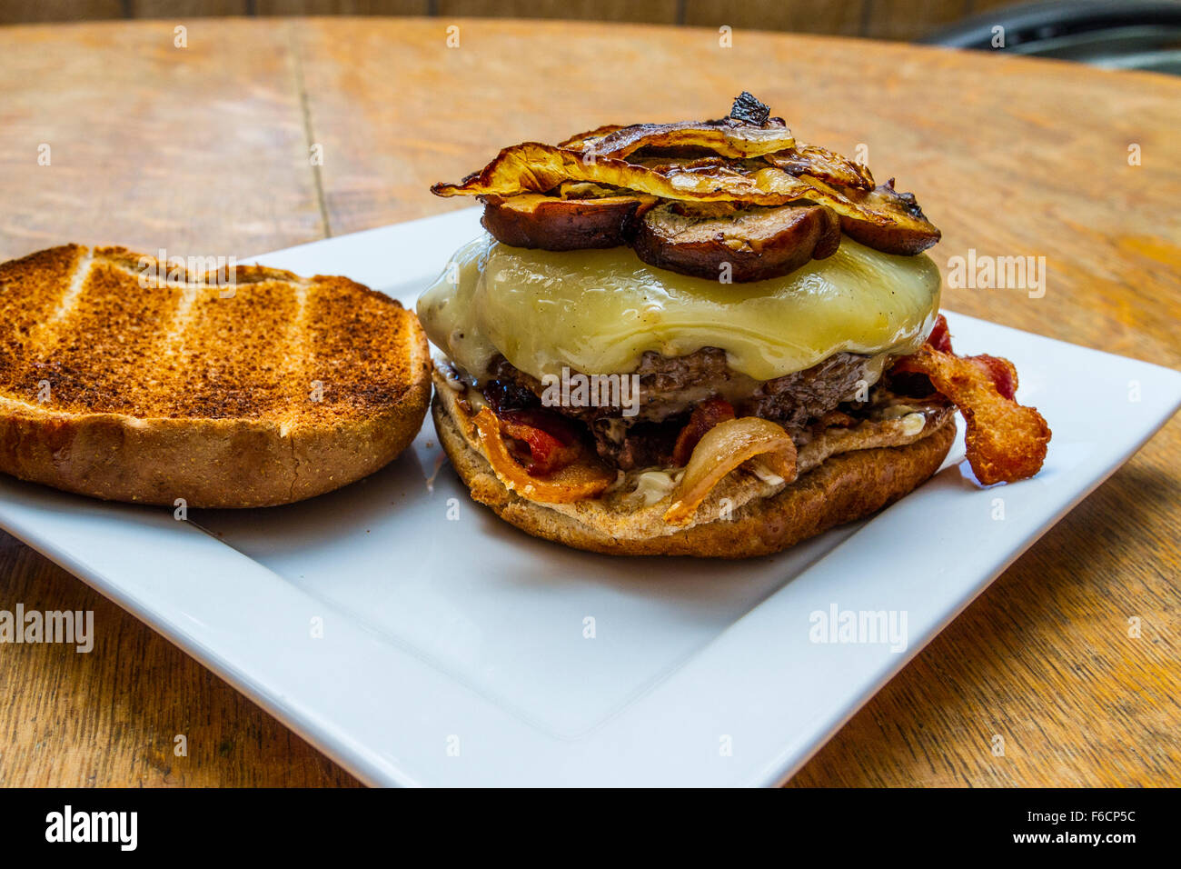 Un fungo, svizzero, la pancetta, il soffritto di cipolla, hamburger su un intero tostato bun di frumento Foto Stock