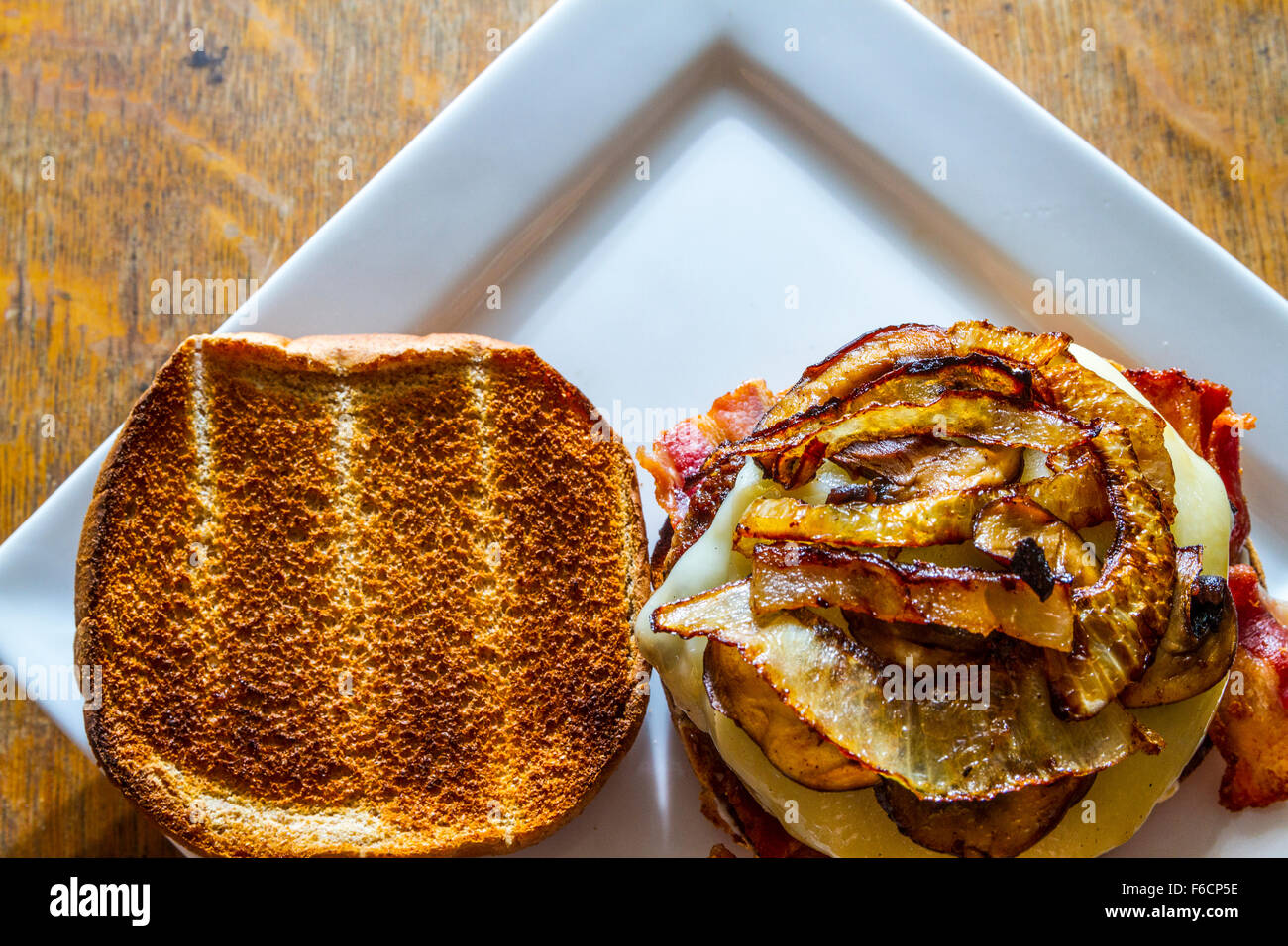 Un fungo, svizzero, la pancetta, il soffritto di cipolla, hamburger su un intero tostato bun di frumento Foto Stock