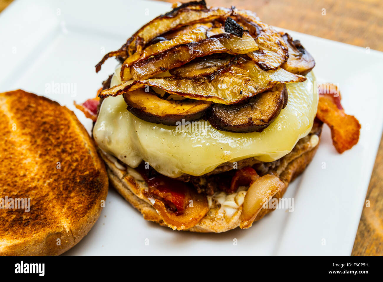 Un fungo, svizzero, la pancetta, il soffritto di cipolla, hamburger su un intero tostato bun di frumento Foto Stock