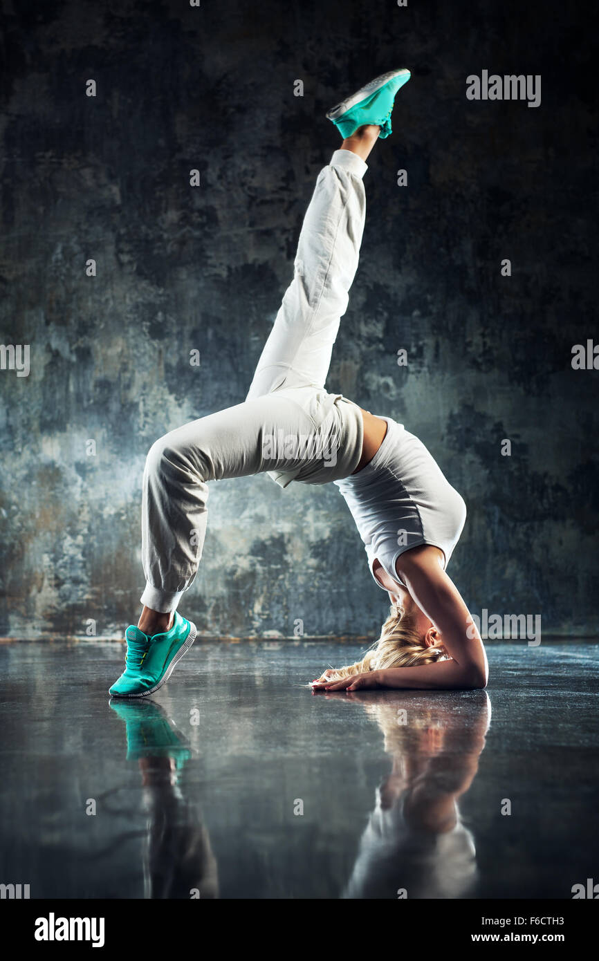 Donna giovane ballerino di danza moderna in bianco. Sulla pietra scura sullo sfondo della parete. Foto Stock