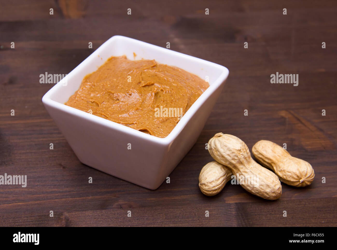 Ciotola con burro di arachidi sul tavolo di legno Foto Stock