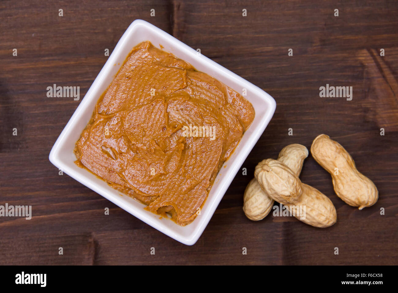 Ciotola con burro di arachidi sul tavolo di legno vista superiore Foto Stock