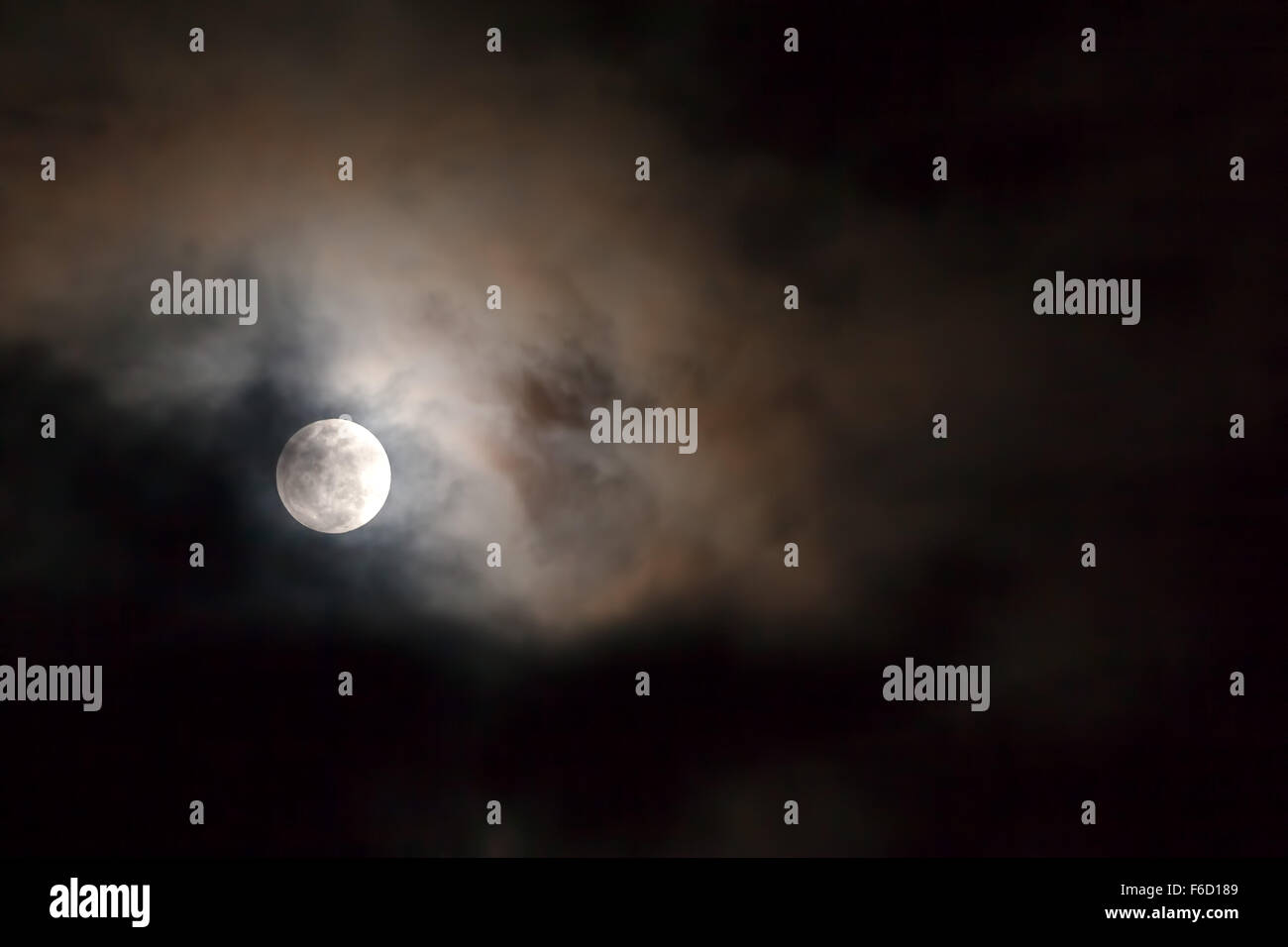 Luna piena sopra nero scuro cielo con le stelle e le nuvole Foto Stock