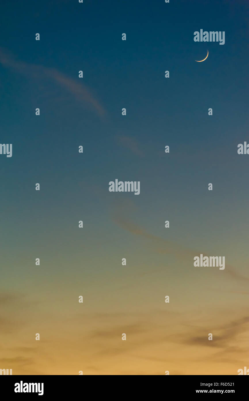 Una falce di luna si blocca in un colorato tramonto Cielo. Foto Stock