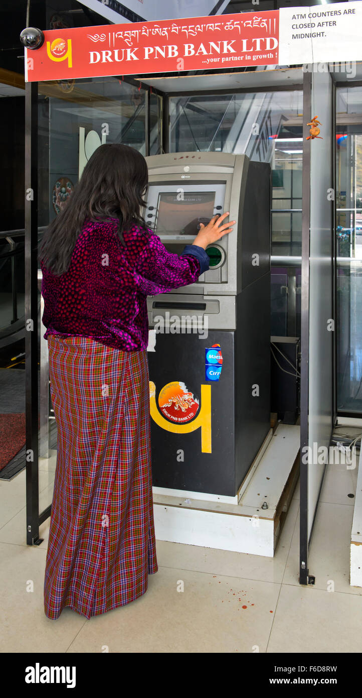 La donna nel tradizionale abito Butanesi presso un Bancomat della Druk PNB Banca, Thimphu Bhutan Foto Stock