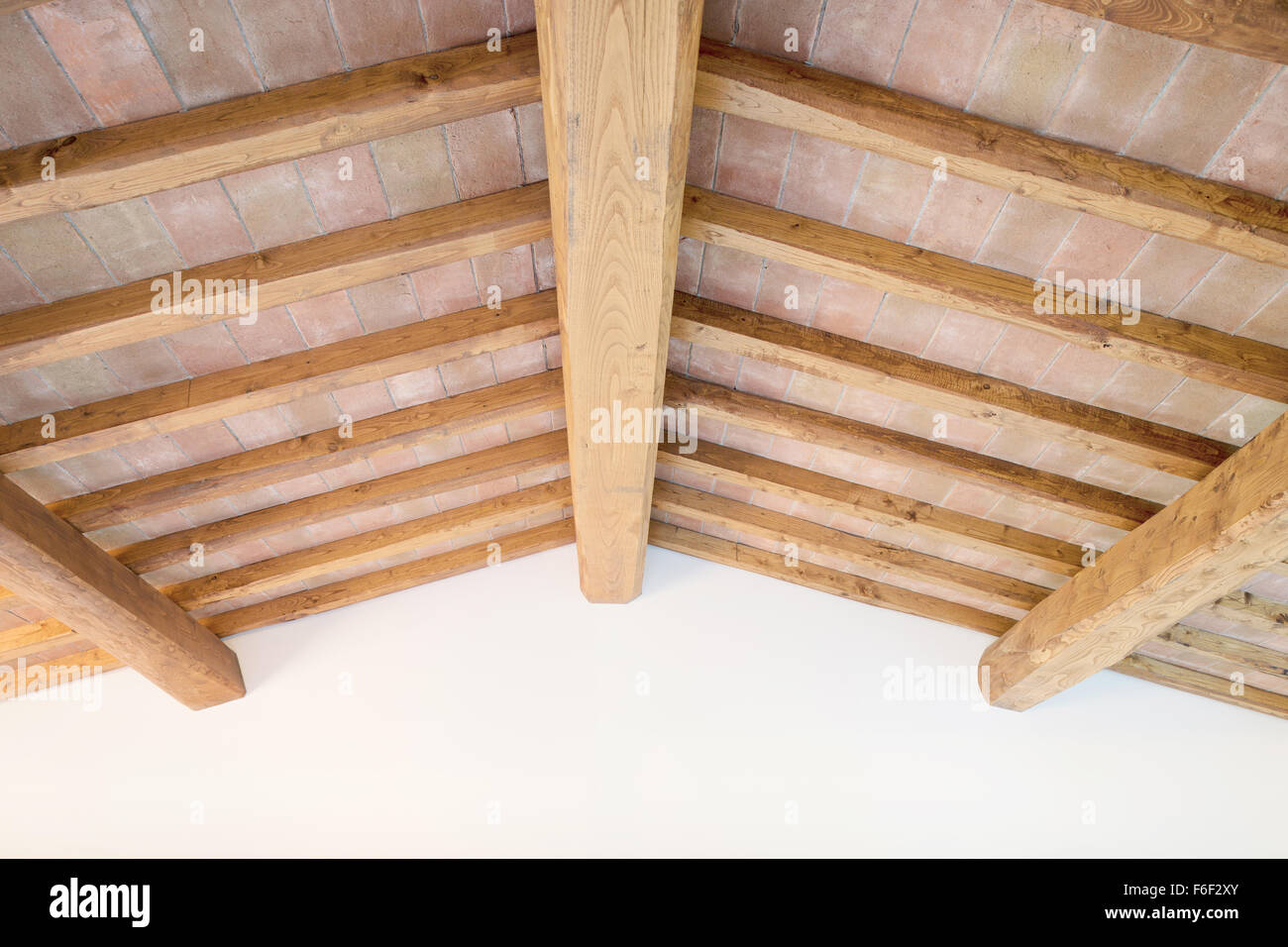 Tradizionale Toscano oak trave di legno sul soffitto di mattoni rossi e modello di parete su sfondo. Classico italiano interni rurale. Foto Stock