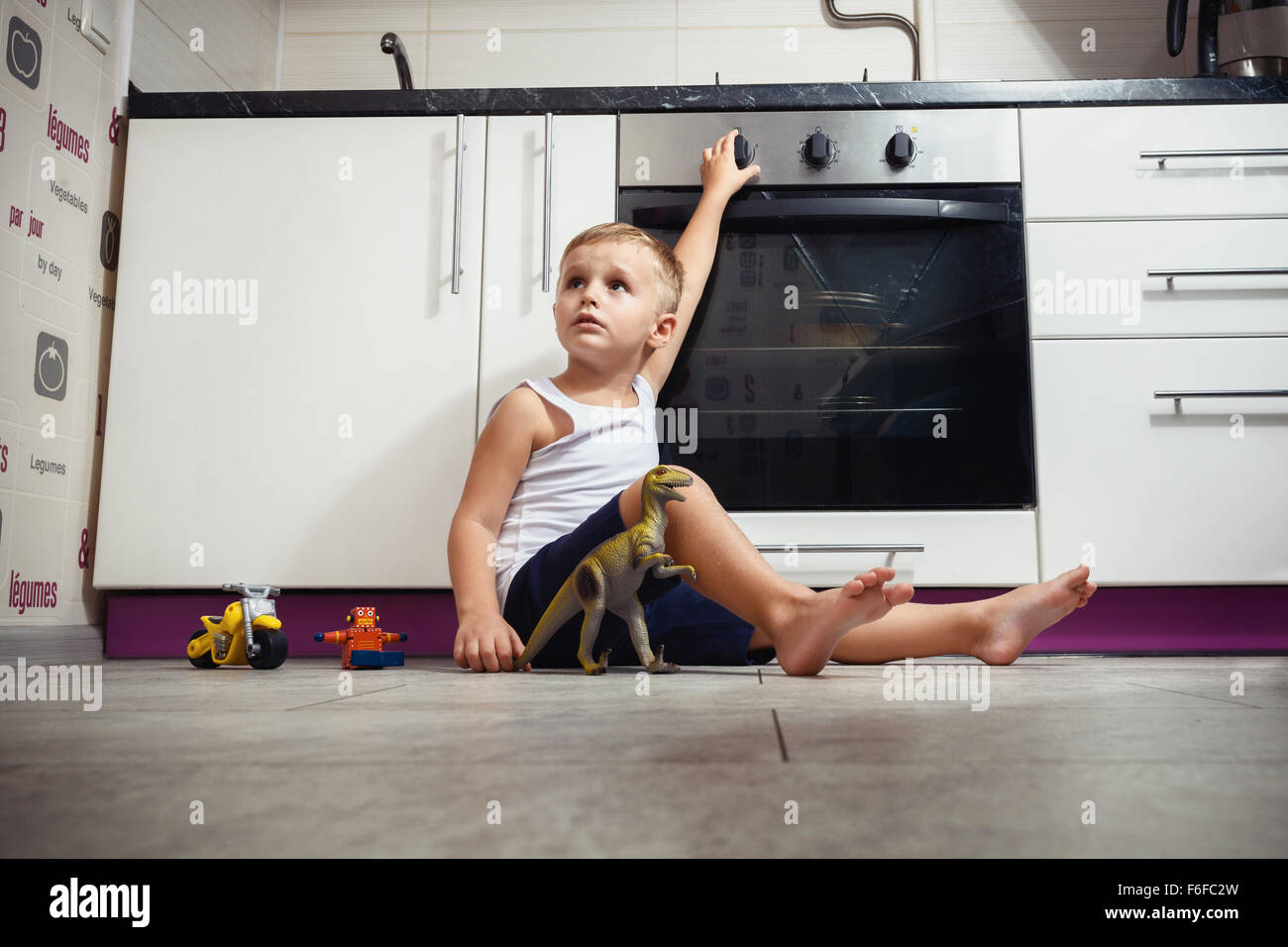 La prevenzione degli incidenti. Il bambino incustodito giocando in cucina con una stufa a gas. senza ritoccare Foto Stock