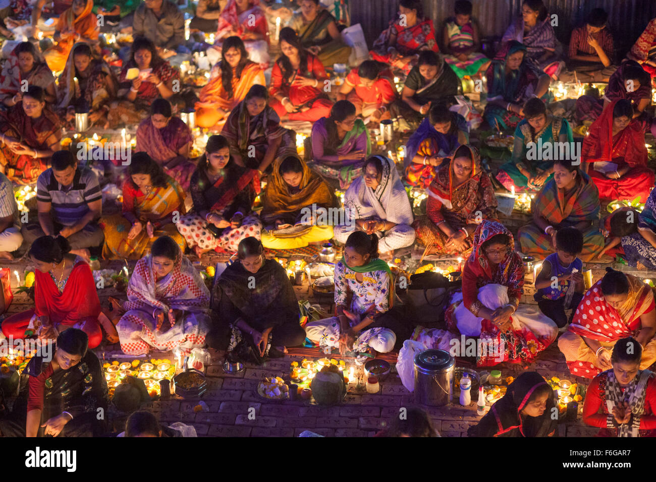 Dacca in Bangladesh. 17 Nov 2015. Migliaia di devoti indù si siede con Prodip e prega Dio di fronte Shri Shri Lokanath Brahmachari Ashram tempio durante il Kartik Brati o Rakher Upobash Dhaka il 17 novembre 2015. Ogni anno migliaia di devoti indù si riuniscono di fronte di Shri Shri Lokenath Brahmachari Ashram tempio per il Kartik Brati o Rakher Upobash festival religioso in Barodi, vicino a Dacca in Bangladesh. Fedeli di sedersi di fronte luce delle candele ( chiamato localmente come Prodip ) e assorbire nella preghiera...Lokenath Brahmachari chi è chiamato Baba Lokenath era un 18t Foto Stock