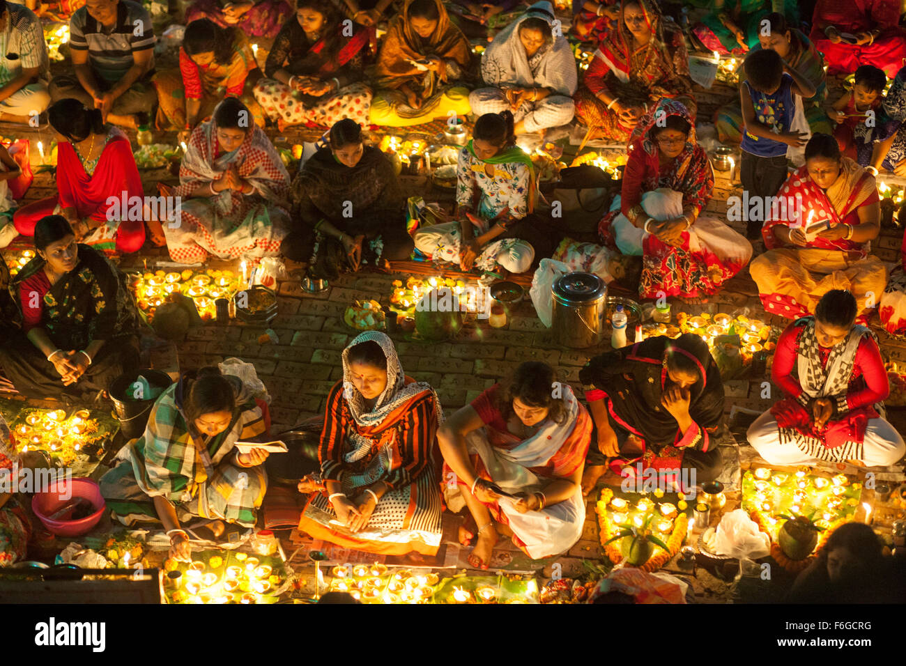 Dacca in Bangladesh. 17 Nov 2015. Migliaia di devoti indù si siede con Prodip e prega Dio di fronte Shri Shri Lokanath Brahmachari Ashram tempio durante il Kartik Brati o Rakher Upobash Dhaka il 17 novembre 2015. Ogni anno migliaia di devoti indù si riuniscono di fronte di Shri Shri Lokenath Brahmachari Ashram tempio per il Kartik Brati o Rakher Upobash festival religioso in Barodi, vicino a Dacca in Bangladesh. Fedeli di sedersi di fronte luce delle candele ( chiamato localmente come Prodip ) e assorbire nella preghiera...Lokenath Brahmachari chi è chiamato Baba Lokenath era un 18t Foto Stock