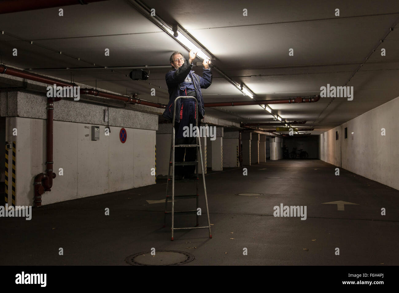 Modifiche del custode di una lampada fluorescente in un parcheggio sotterraneo. Foto Stock