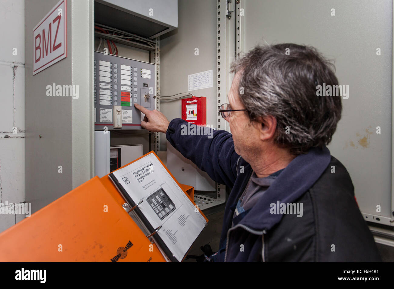 Custode controlla una centrale di sistema di allarme antincendio in edificio residenziale. Foto Stock