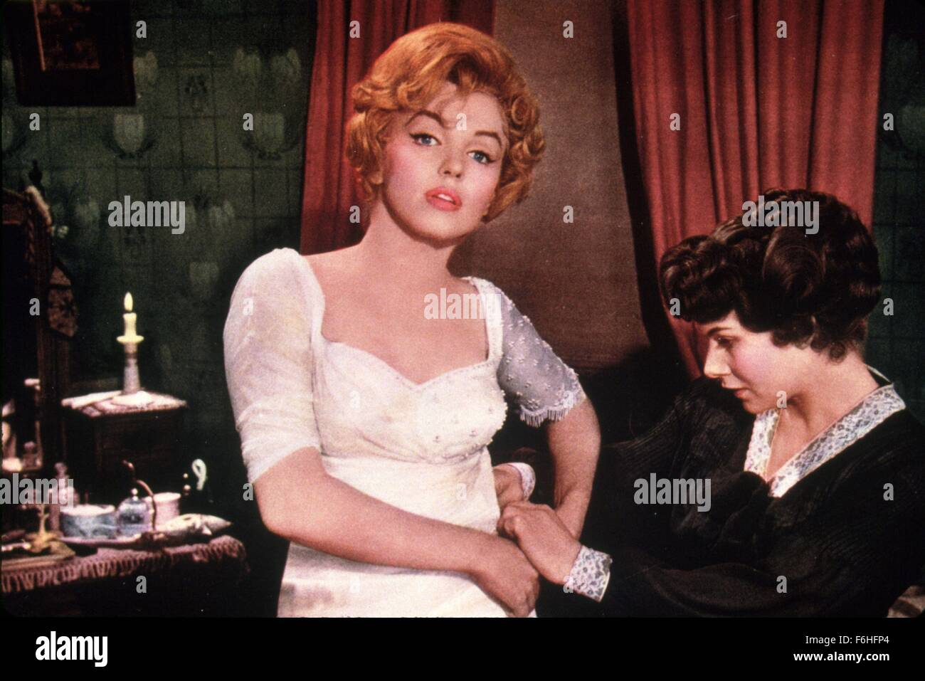 1957, il titolo del film: IL PRINCIPE E LA SHOWGIRL, Direttore: Laurence Olivier, Studio: WARNER, nella foto: MARILYN MONROE, cameriera, spogliatoio, cucitura, sartoria, rammendo, mano su HIP, paziente di servire. (Credito Immagine: SNAP) Foto Stock