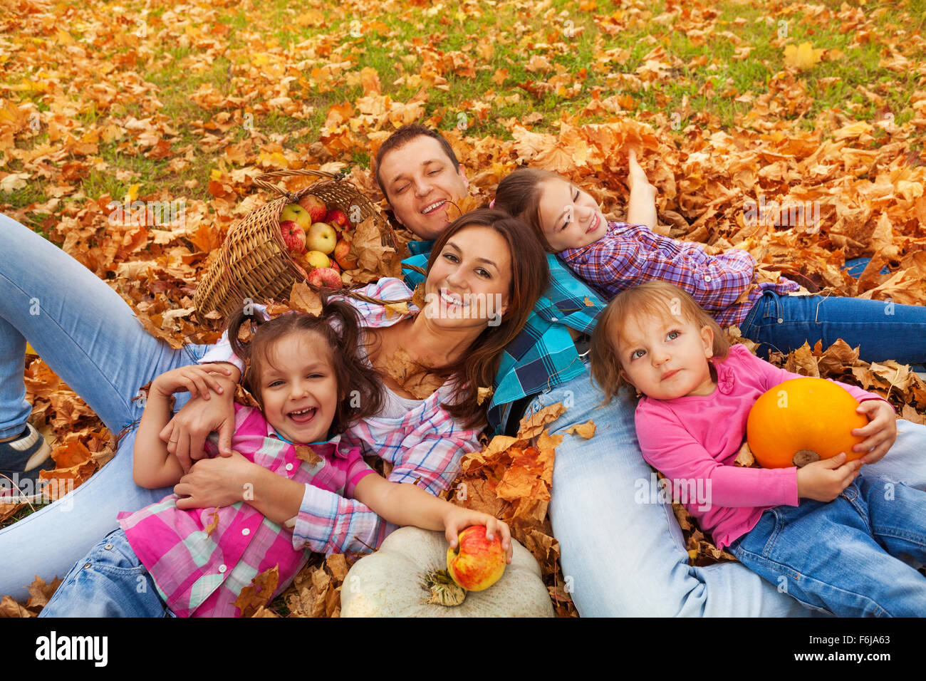 Famiglia con tre ragazze laici in foglie di acero Foto Stock