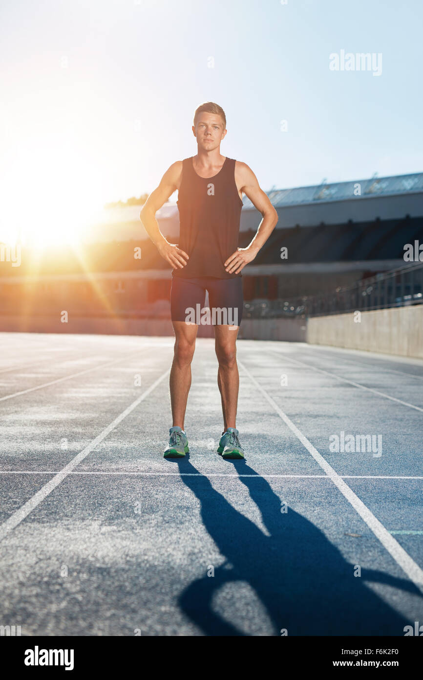 A piena lunghezza shot di professional atleta maschio in piedi con le mani sui fianchi guardando con fiducia alla fotocamera. Sprinter sulla gara tr Foto Stock