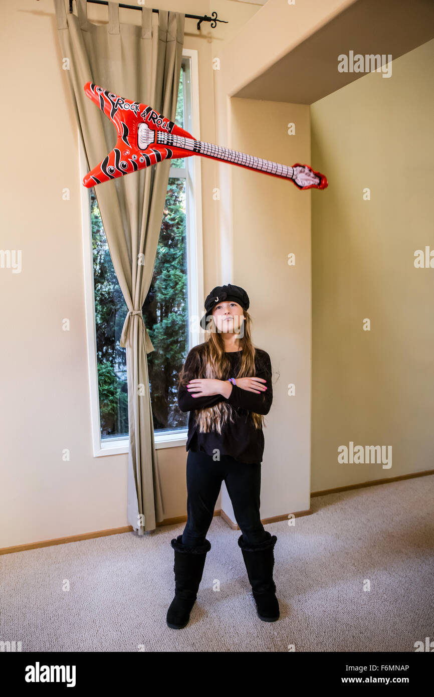 Dieci anni di vecchia ragazza gettando una finta chitarra fino in aria e la cattura di esso, in Issaquah, Washington, Stati Uniti d'America Foto Stock