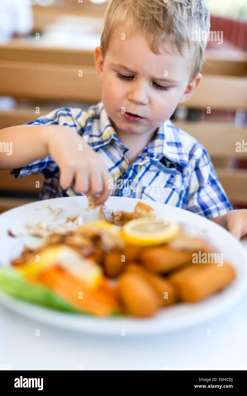 Carino il bambino a mangiare da solo con le mani Foto Stock