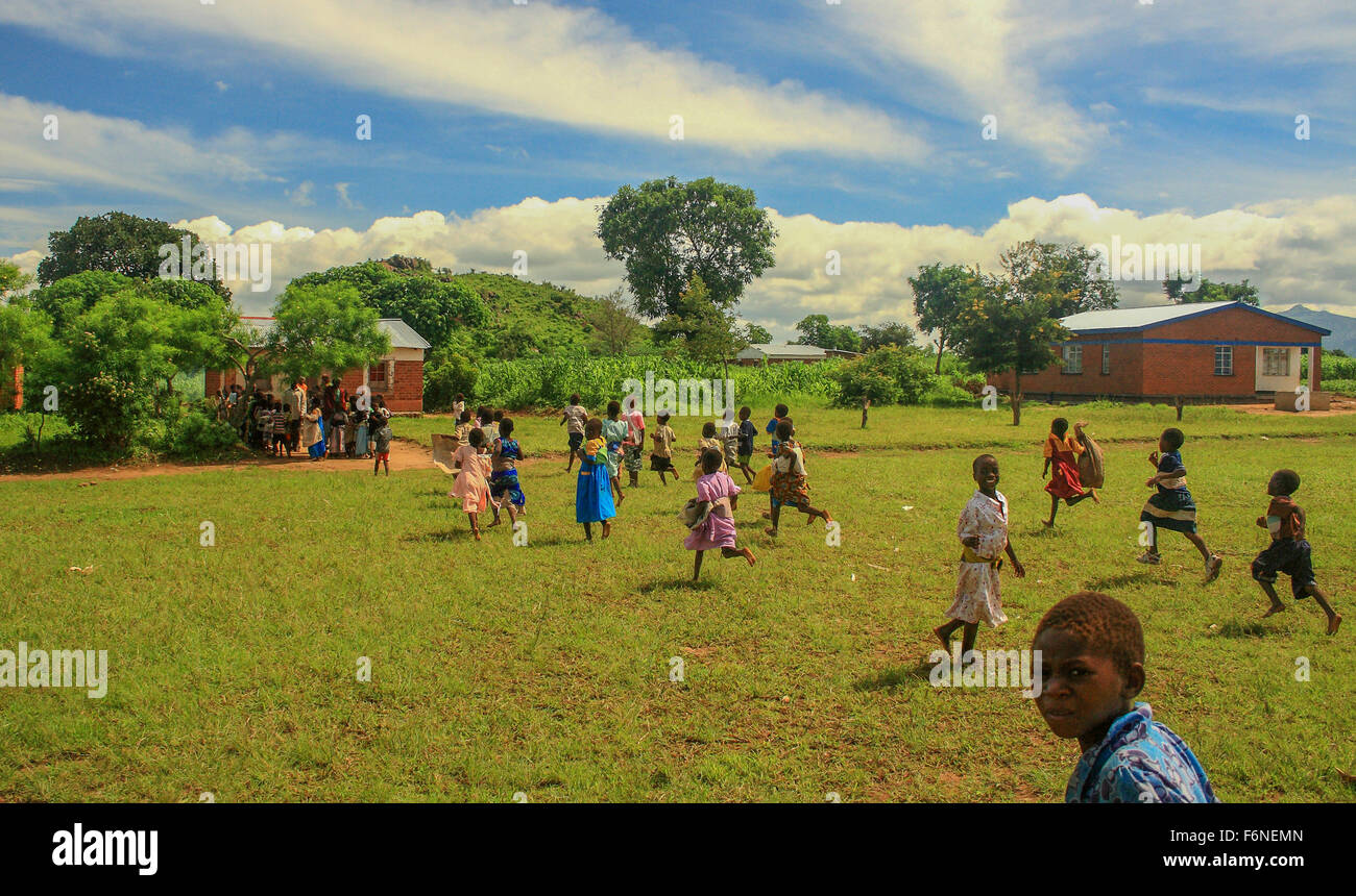 La scuola dei bambini in esecuzione alla coda per il cibo da un programma di alimentazione nel villaggio di Nyombe, Malawi, Africa Foto Stock