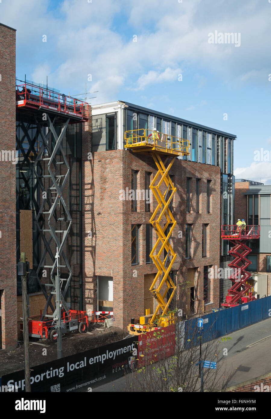 Costruttori utilizzando tre elevatore a pantografo powered access piattaforme durante lavori di costruzione, Durham City, Co. Durham, England, Regno Unito Foto Stock