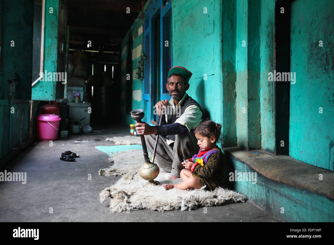 SPITI VALLEY, Uomo seduto con la sua nipote e fumare Hukka nella sua casa di villaggio Rakchham, Sangla, Himachal Pradesh Foto Stock