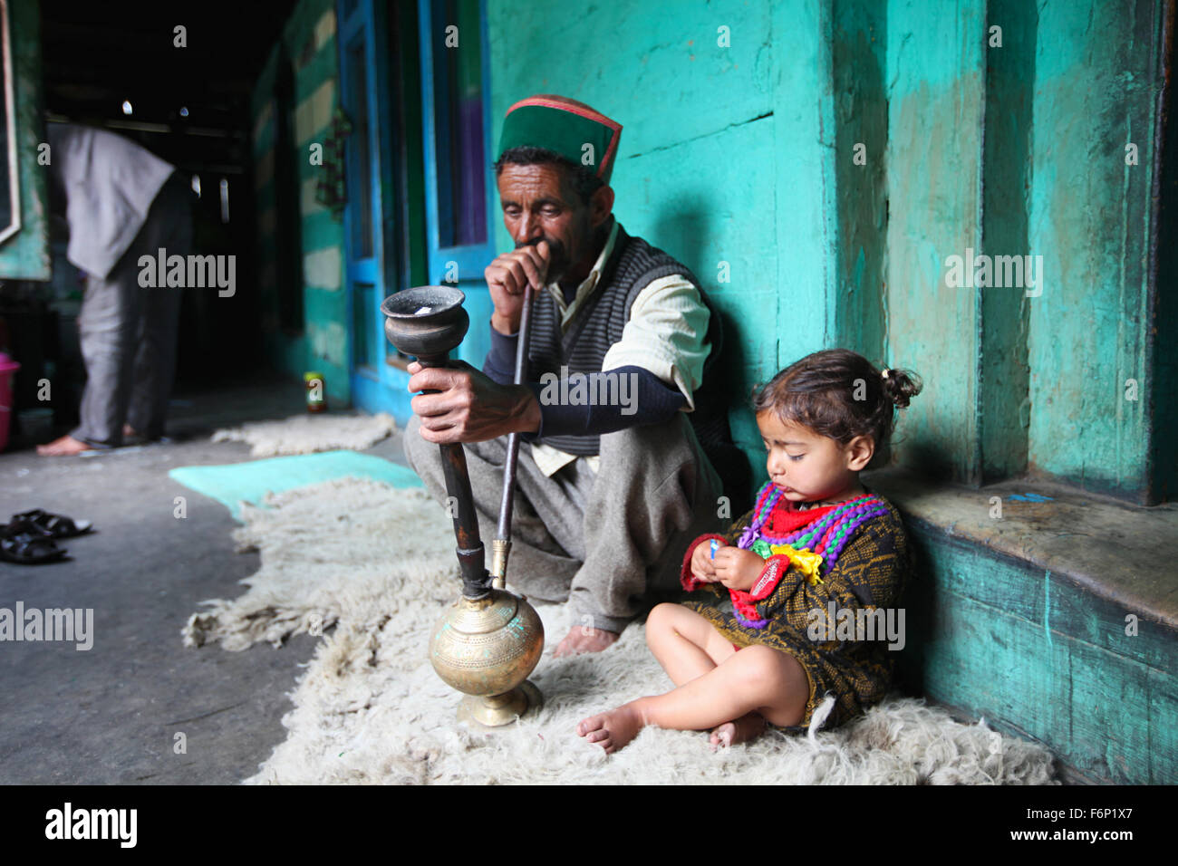 SPITI VALLEY, Uomo seduto con la sua nipote e fumare Hukka nella sua casa di villaggio Rakchham, Sangla, Himachal Pradesh, I Foto Stock