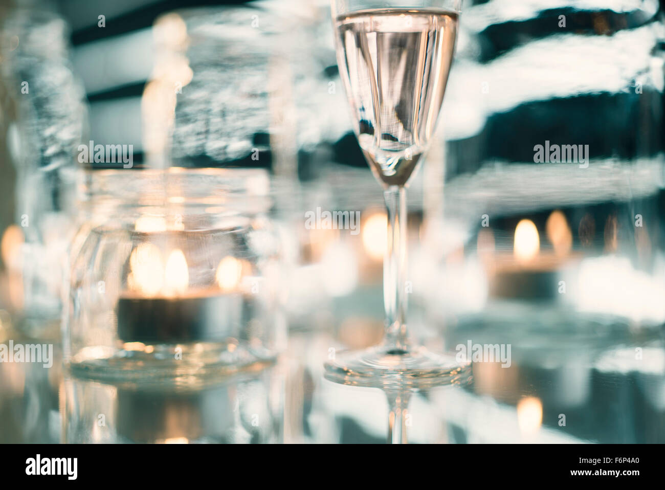 Il vino bianco in vetro e candele in vasetti di vetro Foto Stock