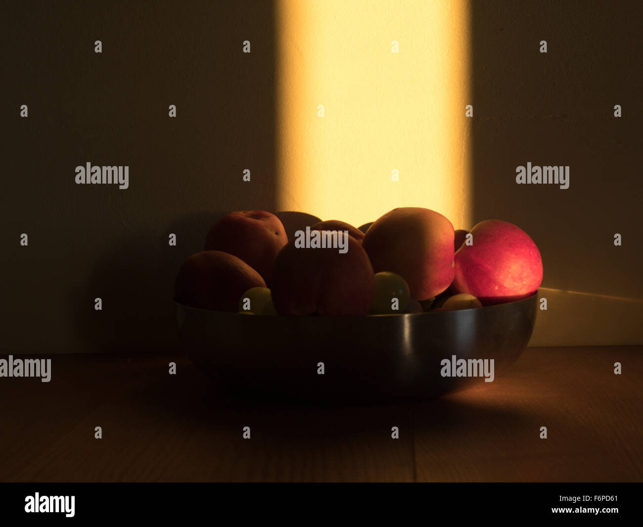 Ancora una vita di arance e mele in una ciotola illuminato da un albero di sunligh da guardare come un dipinto Foto Stock