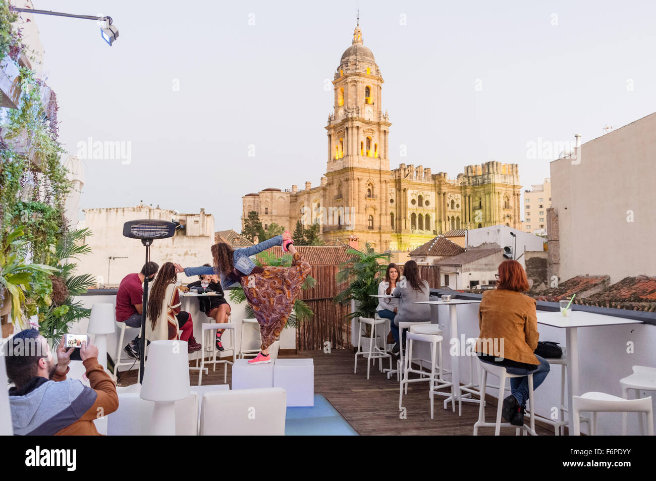 Le persone al bar con terrazza panoramica e duomo illuminato in background. Malaga, Andalusia, Spagna Foto Stock