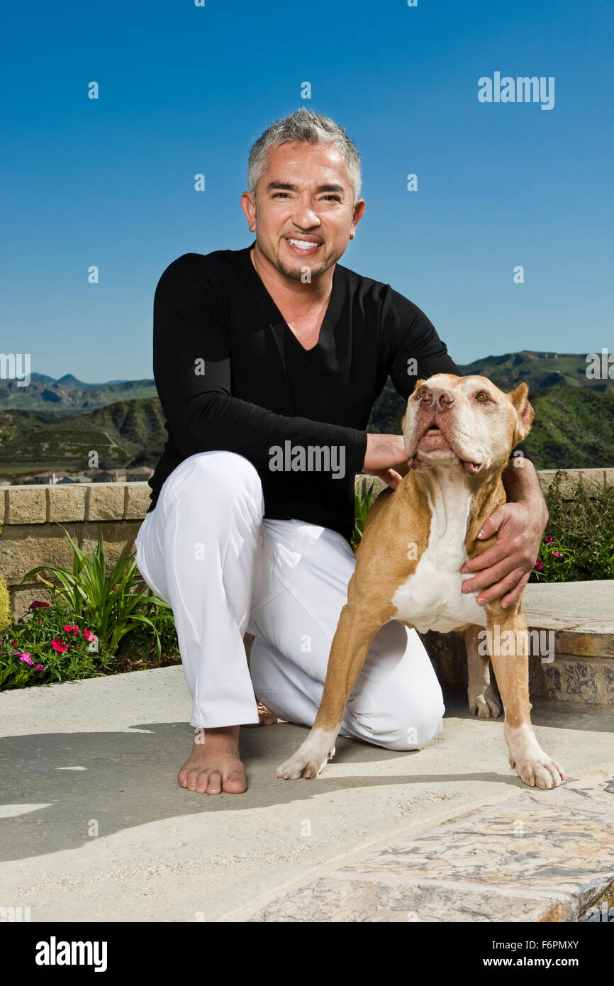 Sorridente a casa Ritratto di inginocchiarsi Ceasr Millan Dog Whisperer famoso TV celebrity trainer con Pitbull cane Daddy Foto Stock