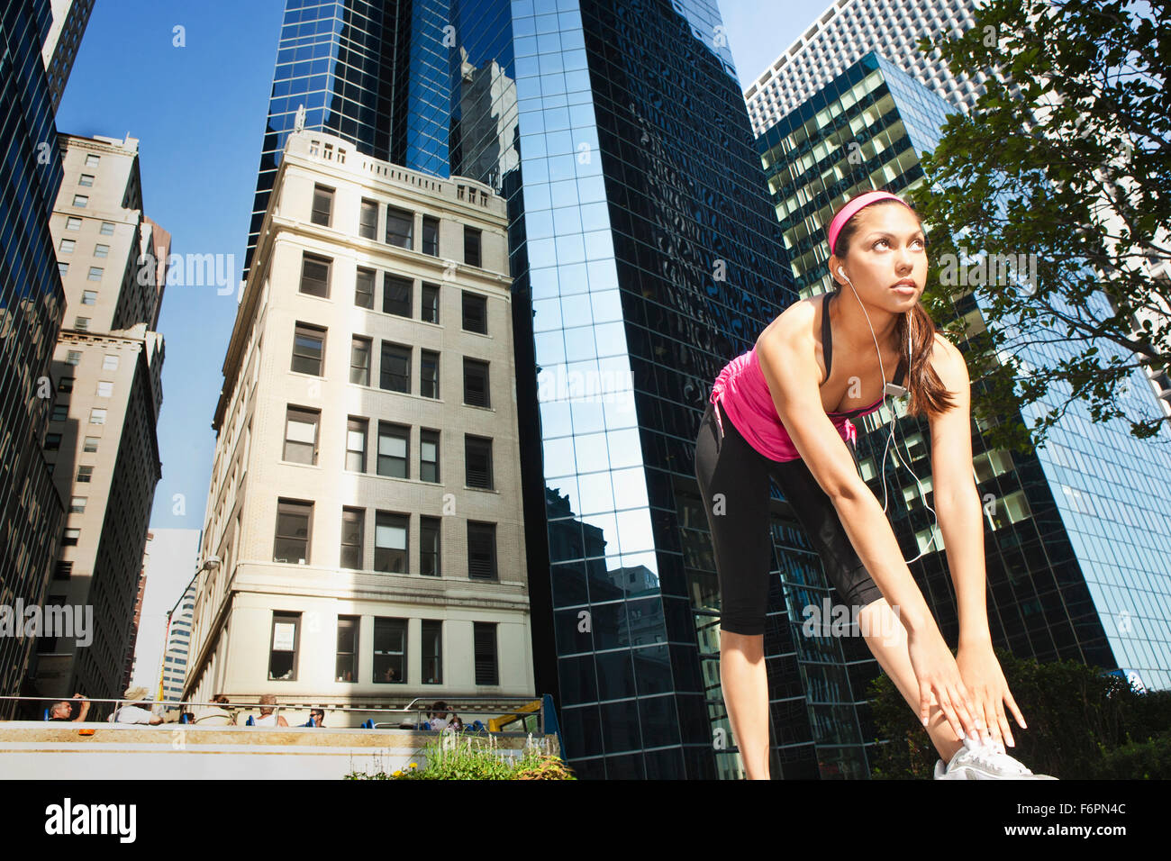 Donna ispanica stretching sotto il grattacielo di edifici Foto Stock