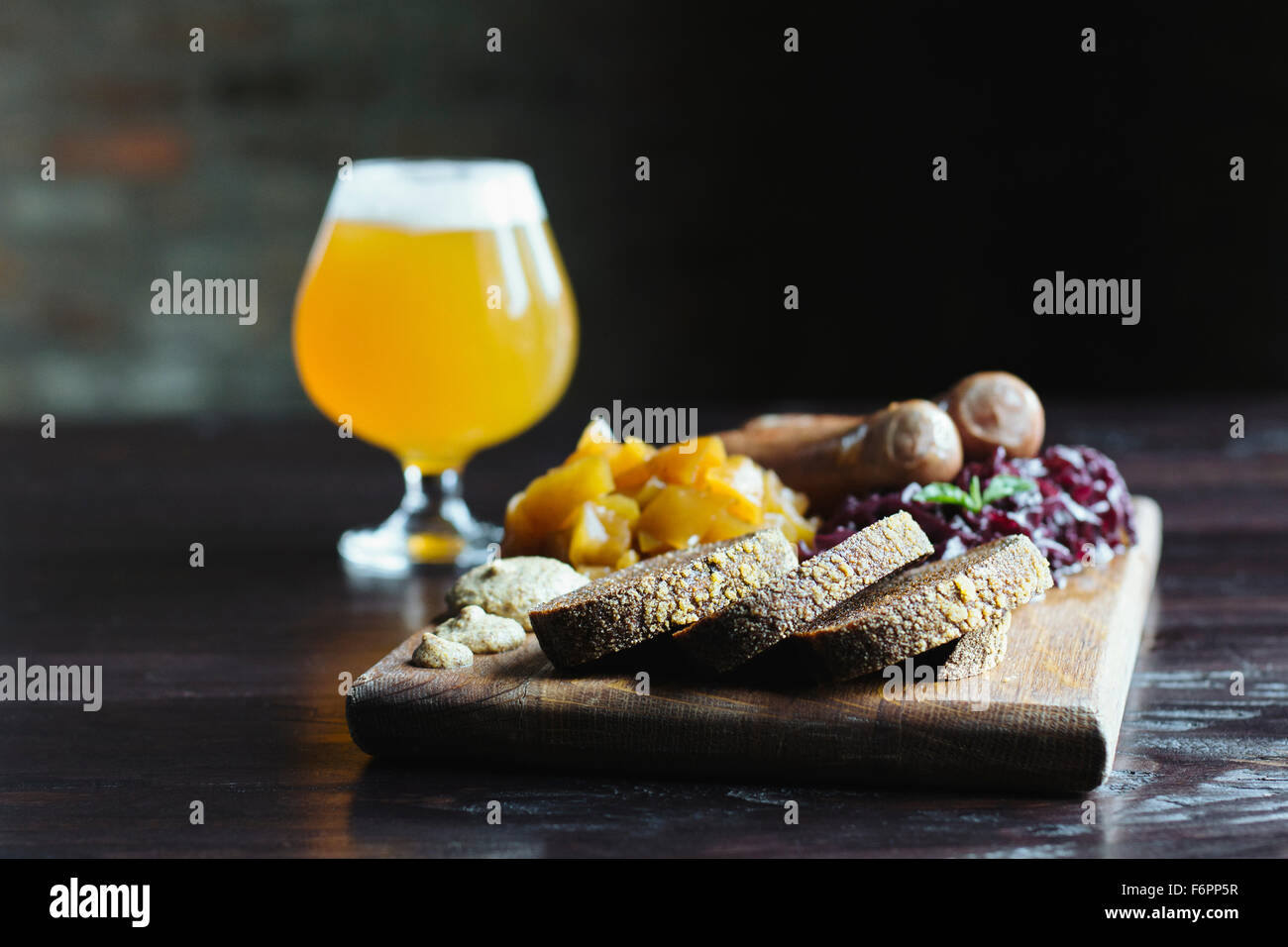 Pane, frutta e formaggi sul tagliere con la birra Foto Stock