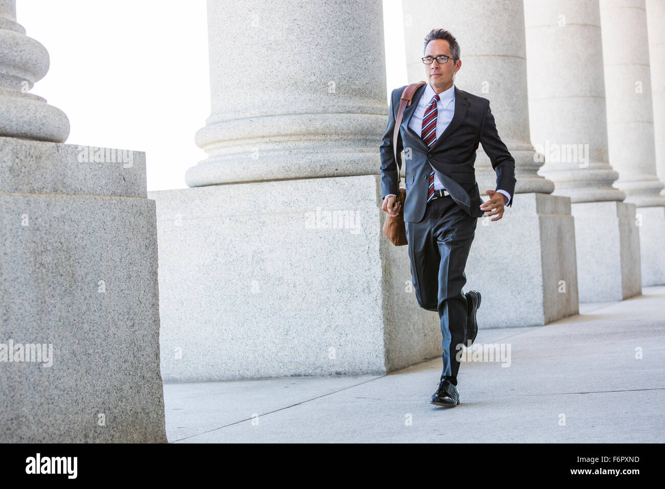 Razza mista imprenditore camminare sotto le colonne Foto Stock