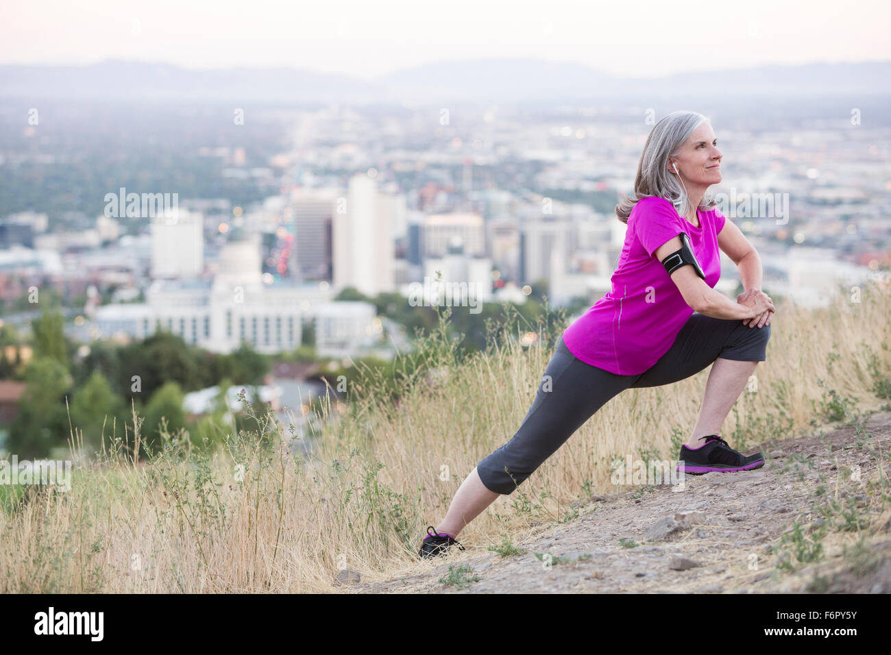 La donna caucasica stiramento sulla collina sopra di Salt Lake City, Utah, Stati Uniti Foto Stock