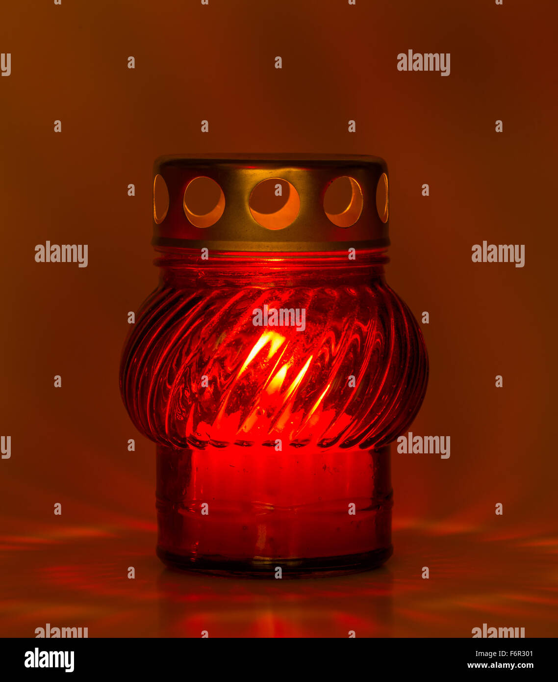 Un vetro rosso tè leggero con una candela interna per illuminare la notte di Natale e altre feste Foto Stock