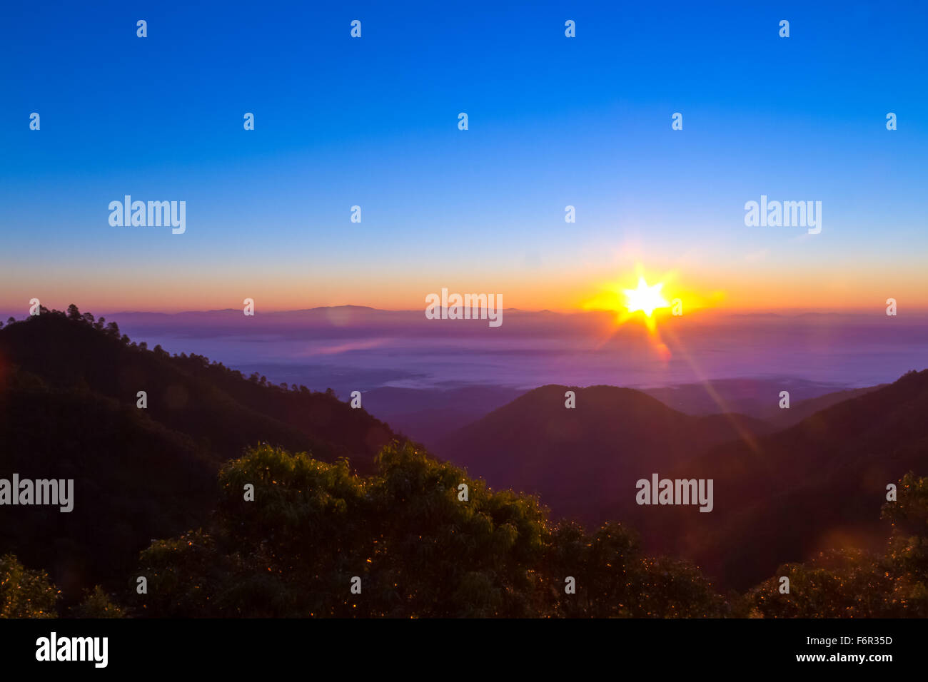 Bella luce dietro la montagna alla mattina il tempo con la nebbia di drifting sopra la città tra due mountain Foto Stock