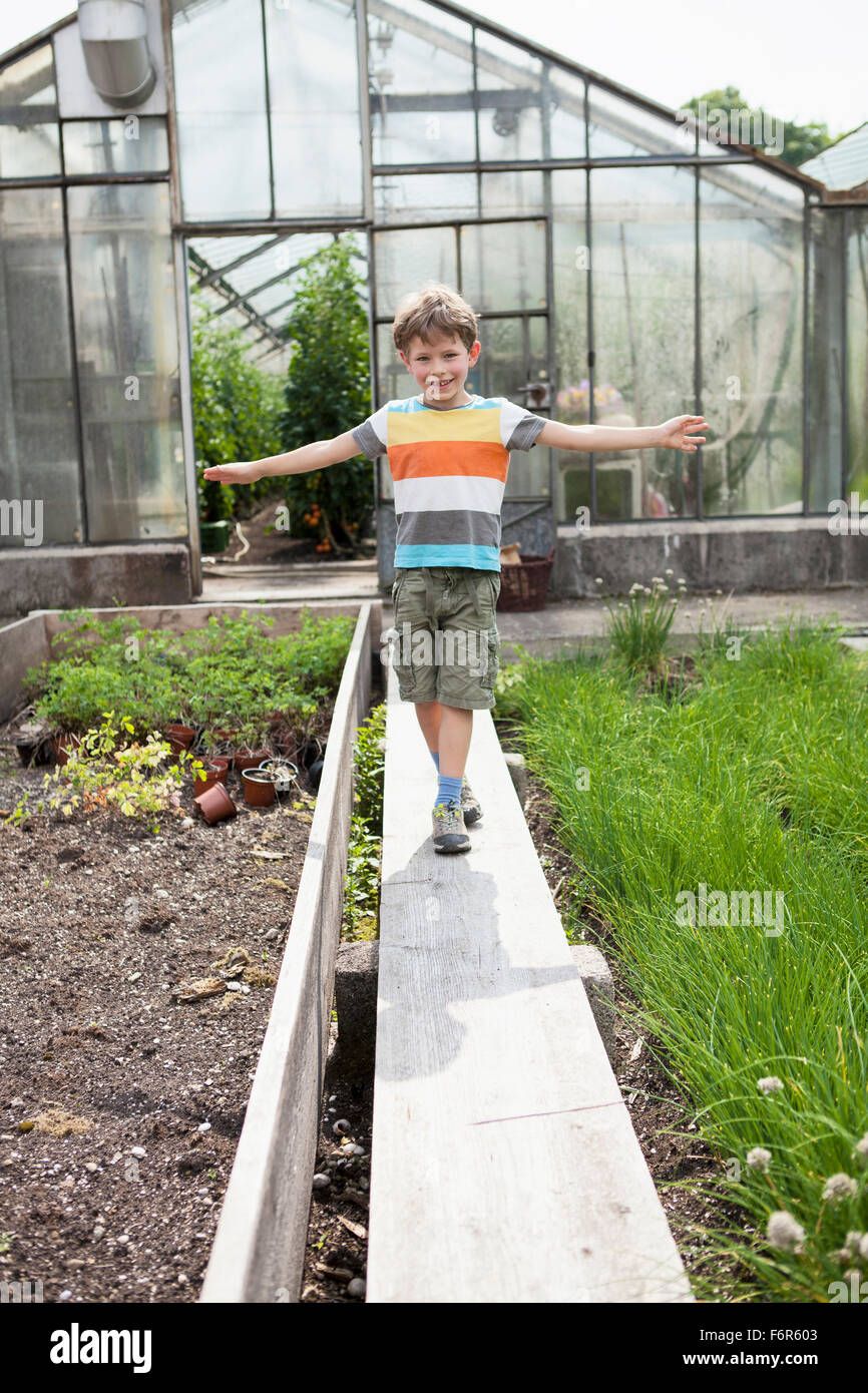 Ragazzo giocando nella parte anteriore della serra Foto Stock