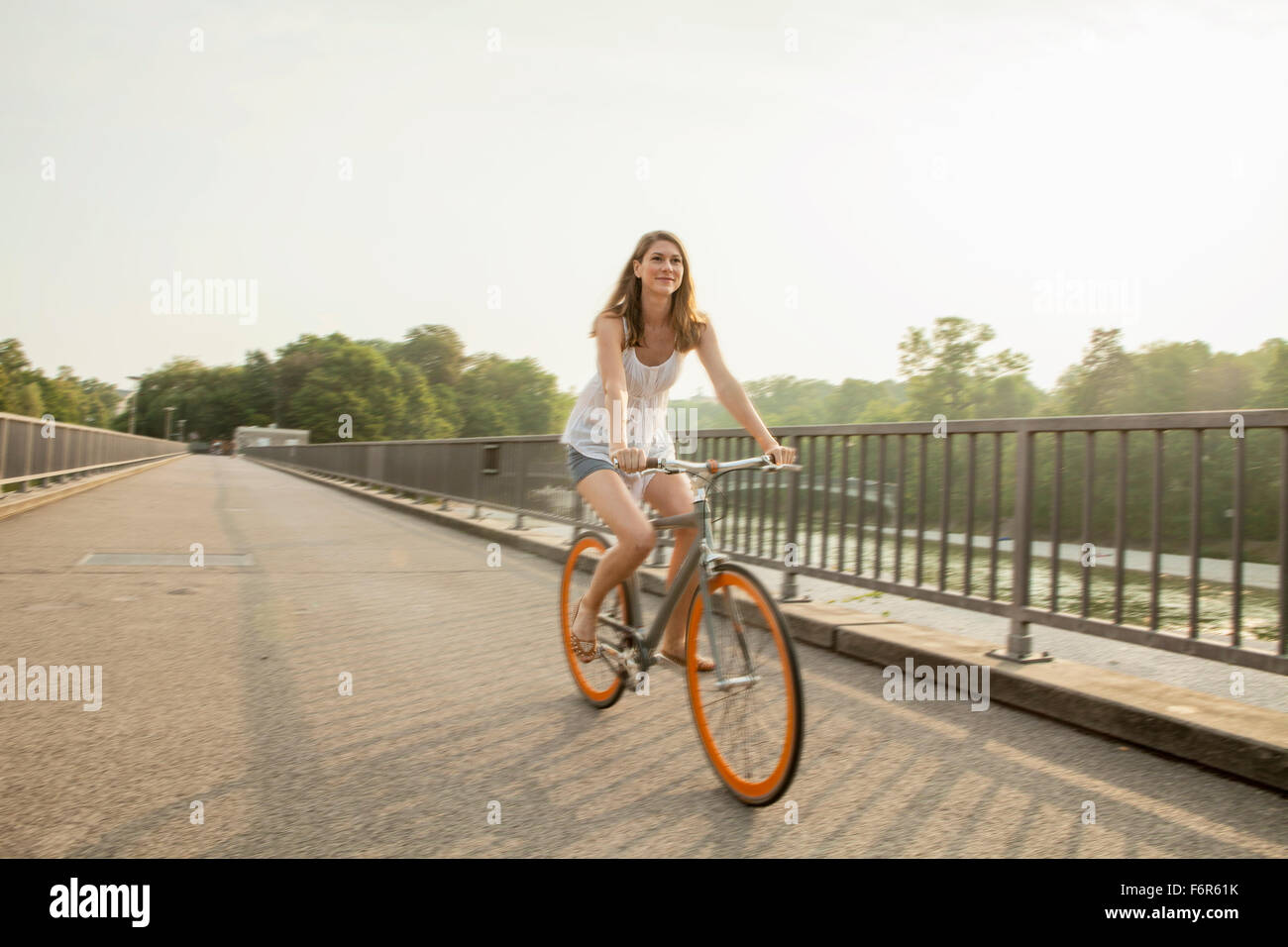 Giovane donna Bicicletta Equitazione sul ponte della città Foto Stock