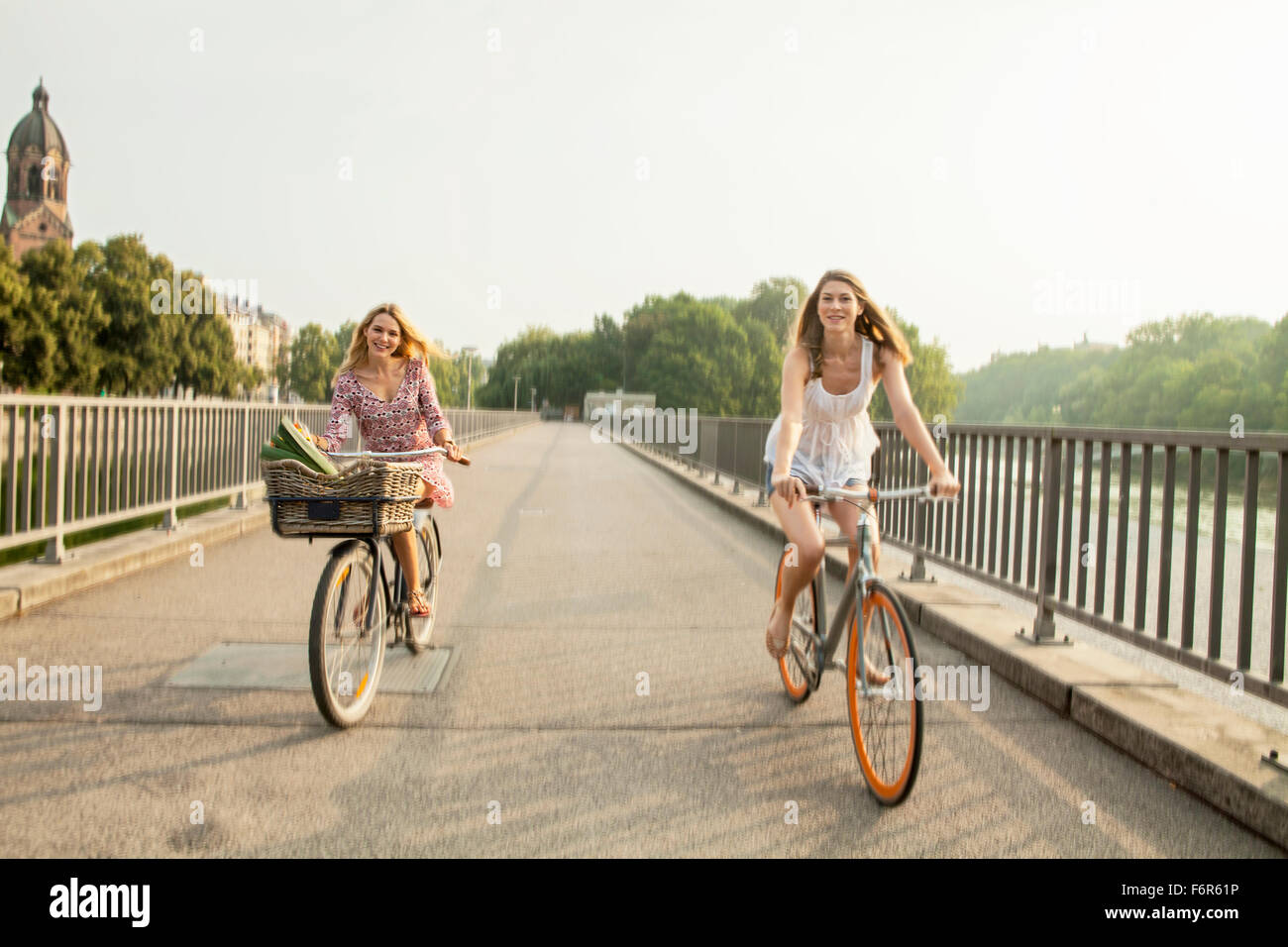 Due donne equitazione Bicicletta sul ponte della città Foto Stock
