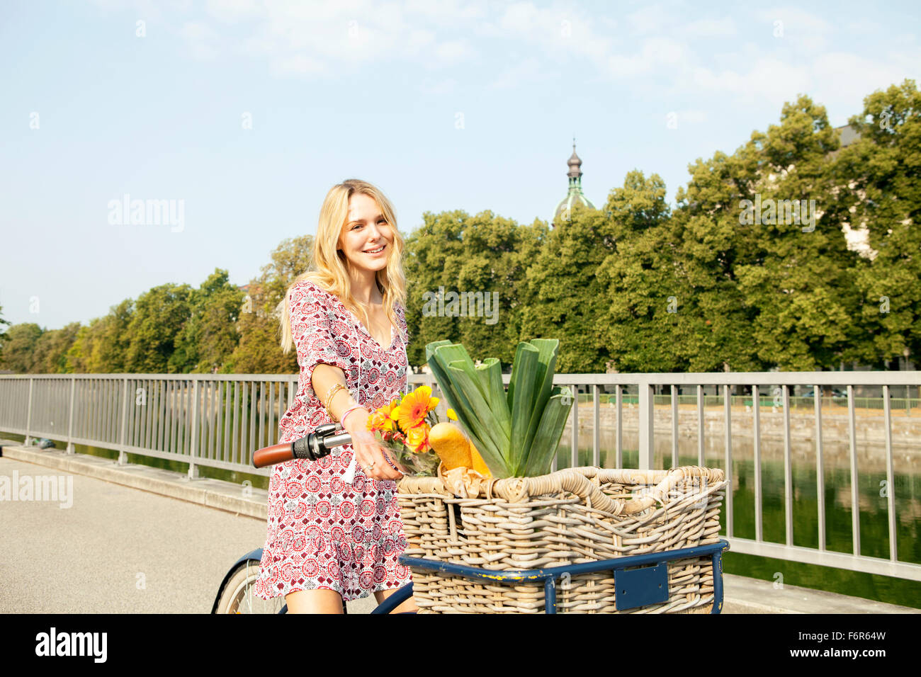Giovane donna con la bicicletta sul ponte della città Foto Stock