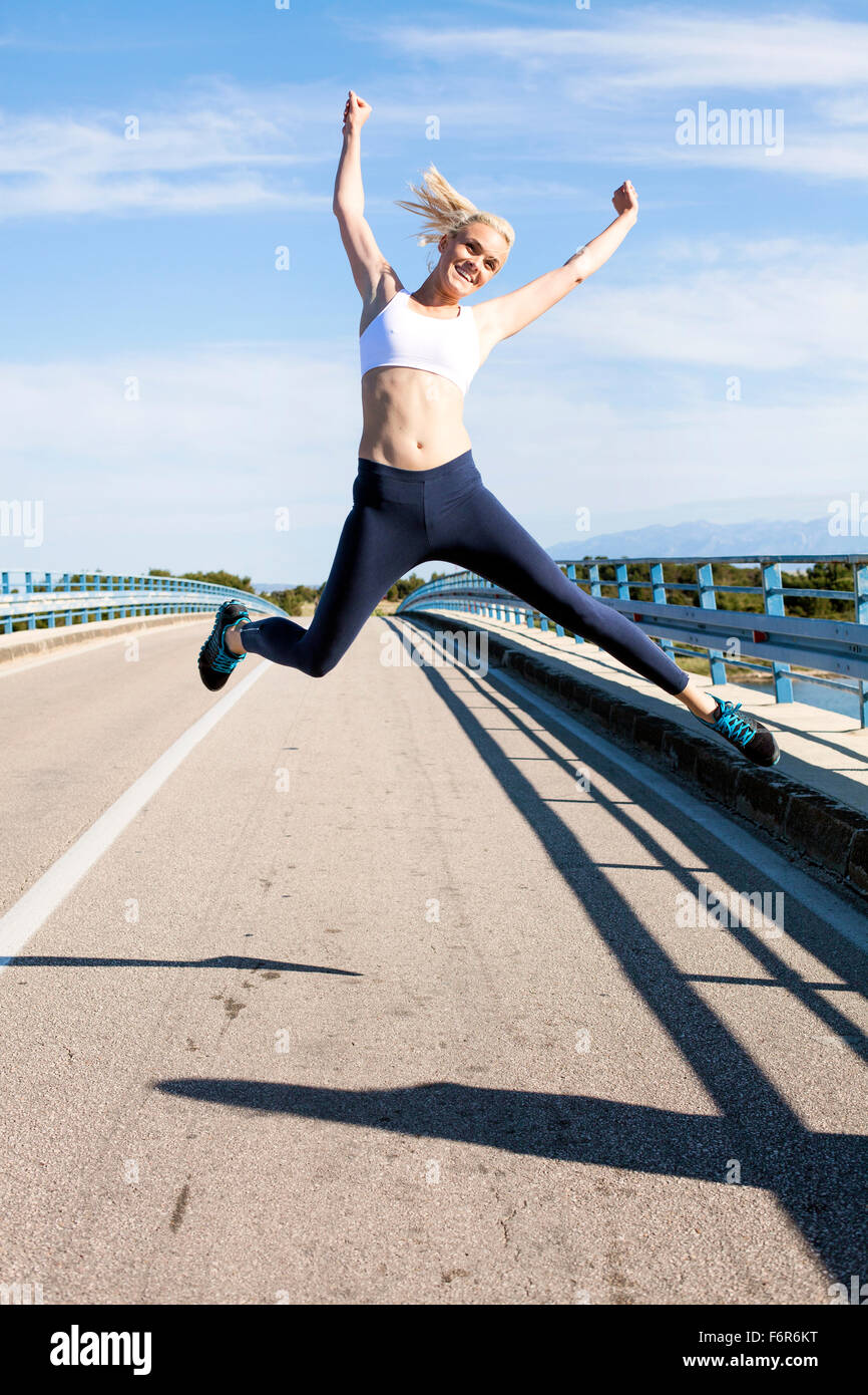 Giovane donna salti di gioia sul lungomare Foto Stock