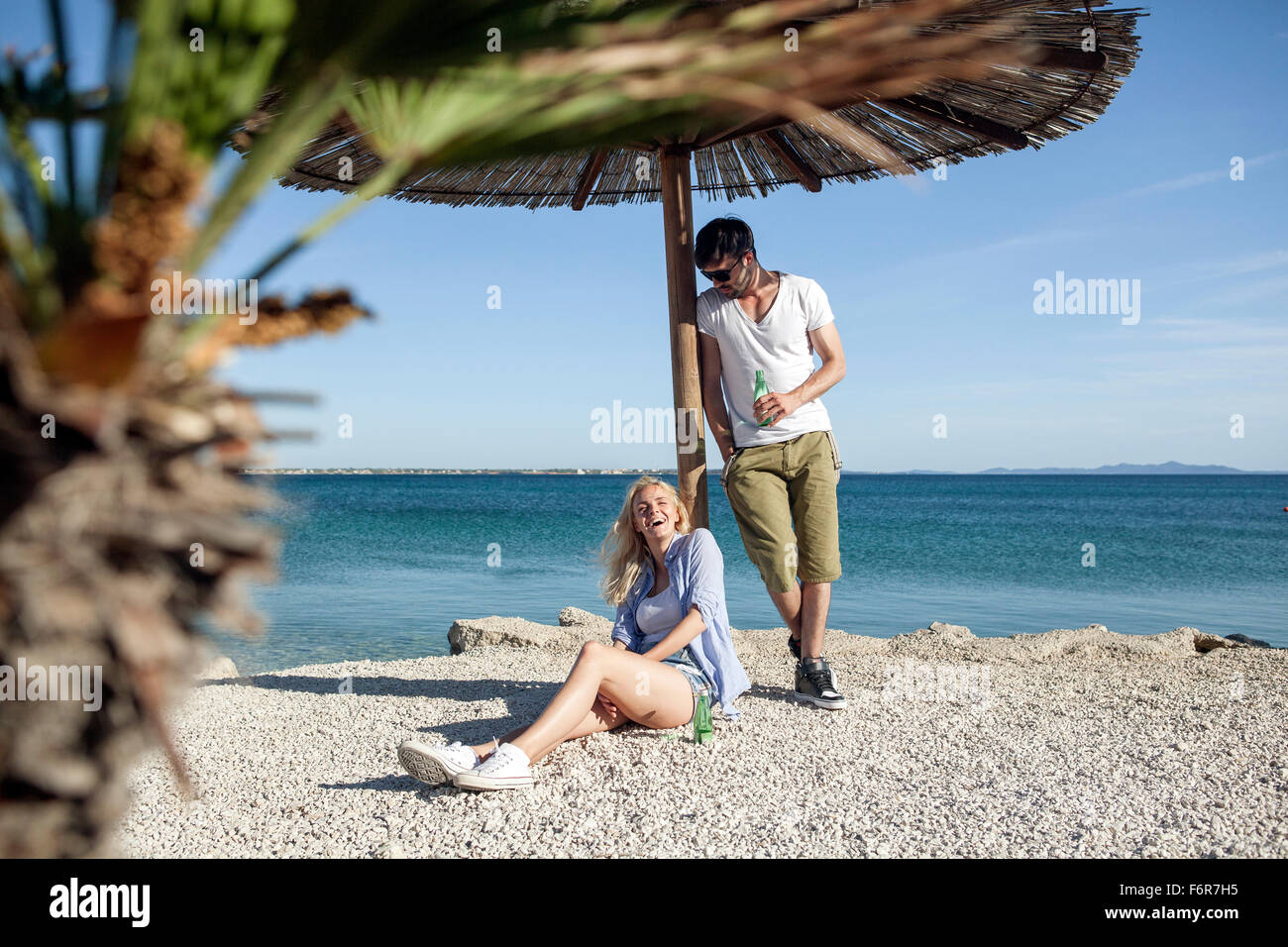 Giovane uomo versando acqua sulla ragazza sulla spiaggia Foto Stock